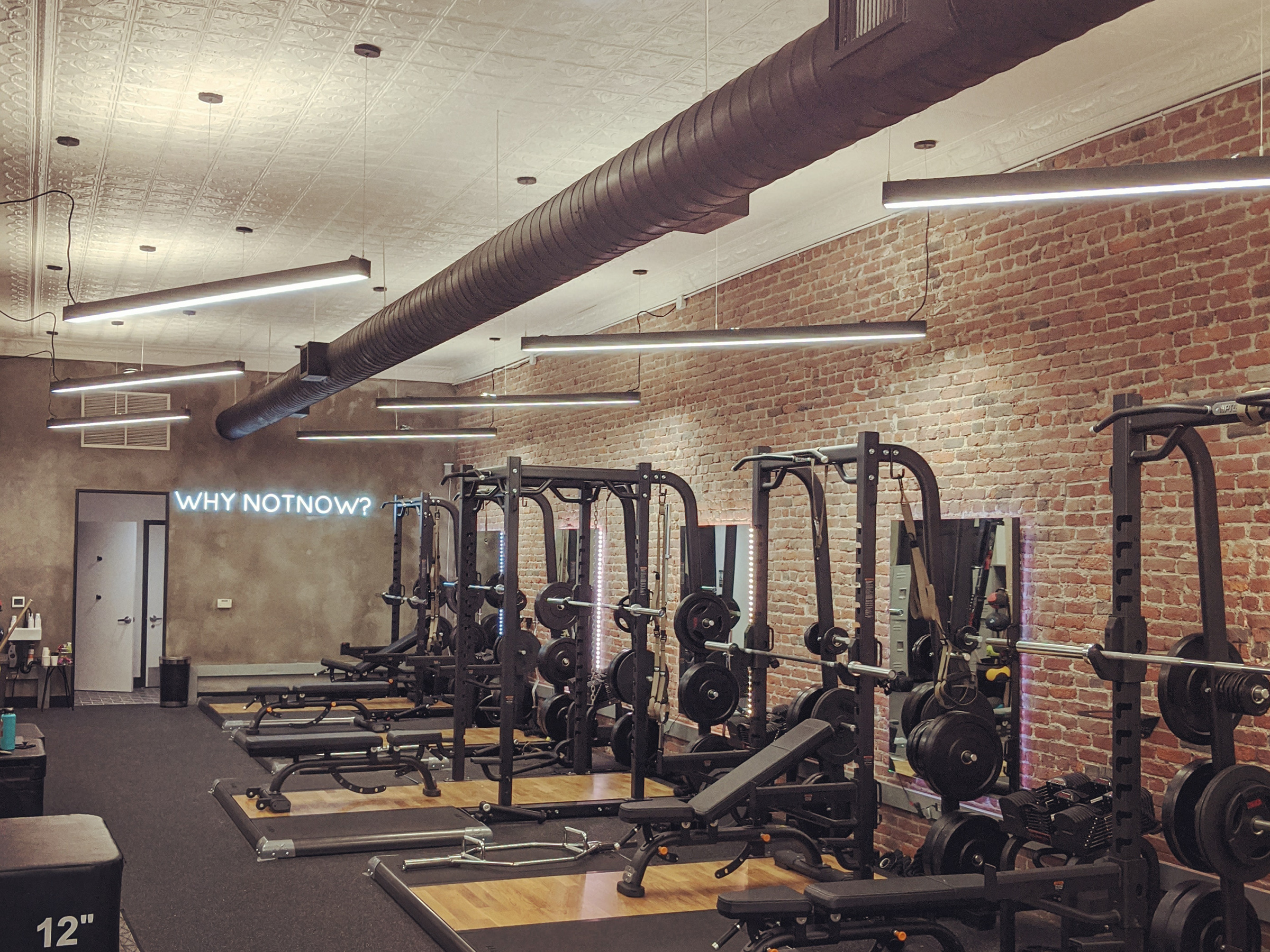 view looking into the fitness room with angled lights and a black duct overhead